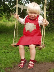 Kinderkleid aus Leder mit Schaf Kind auf der Schaukel